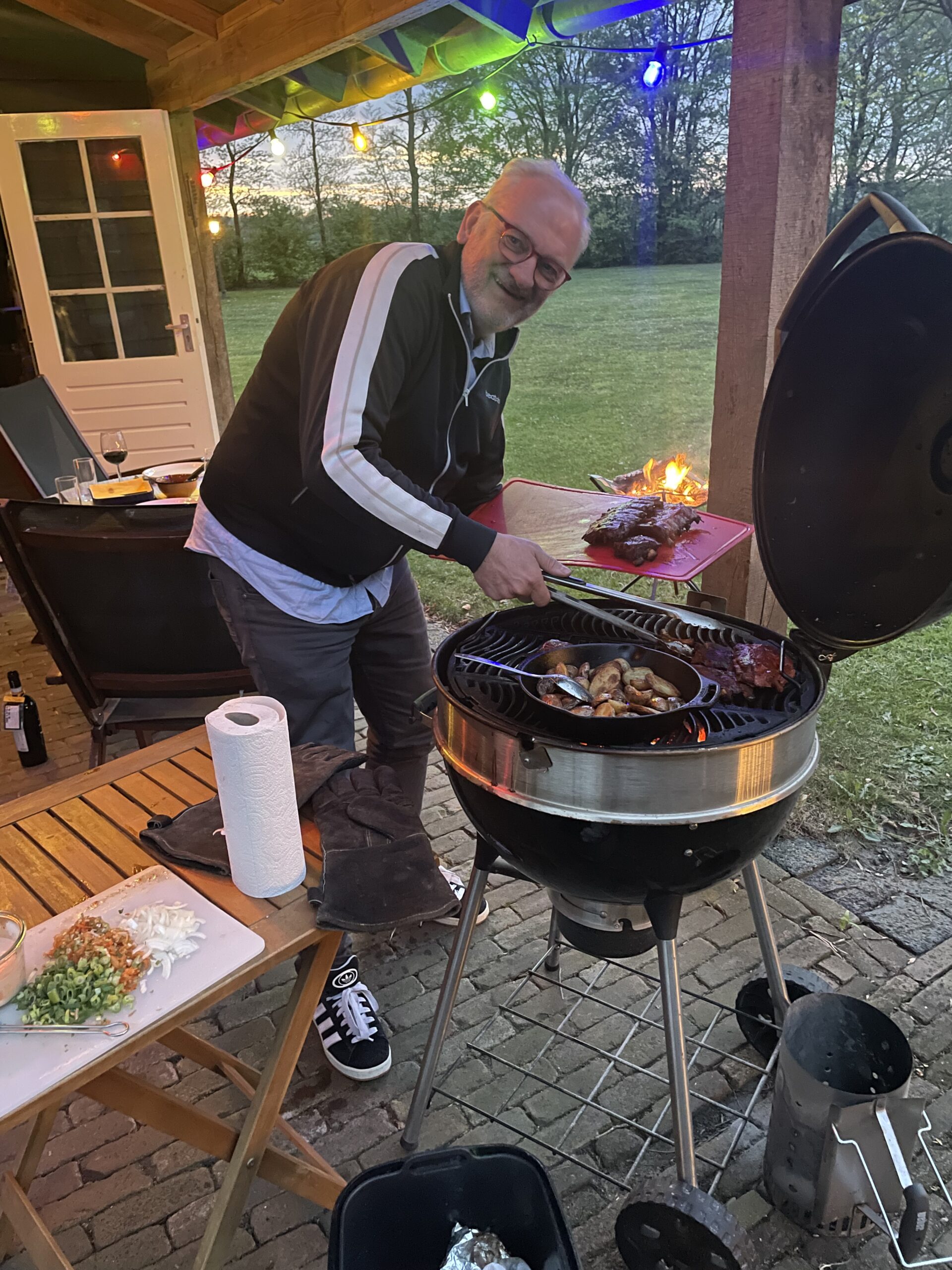 Deelnemer is met barbecue bezig om vlees en krieltjes te grillen