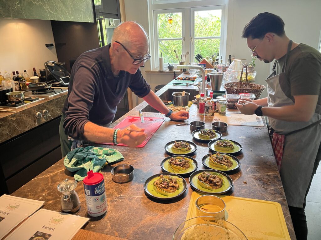 Twee deelnemers maken gezamenlijk gerecht op in de keuken tijdens kookworkshop